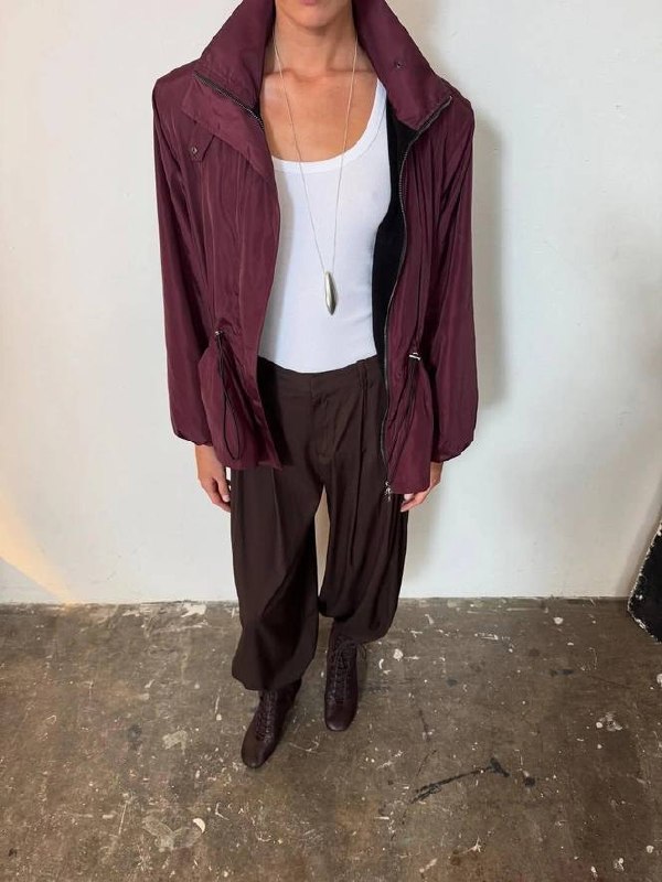 Кадр студийной примерки: марсаловая ветровка на манекенообразной фигуре, белая майка и свободные тёмные брюки — вариант для повседневной стилизации.