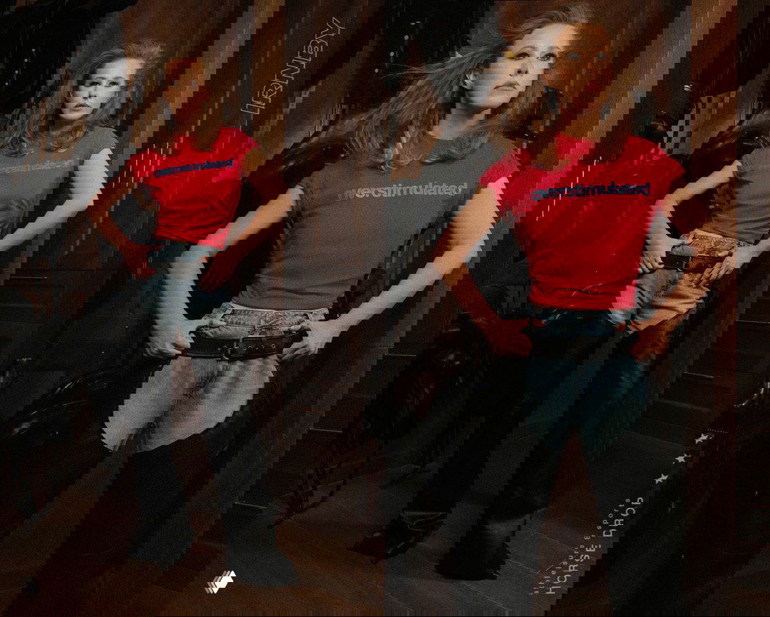 Коллаж вестерн-спортивного образа: джинсовая деталь, чёрные вставки на брюках и яркая футболка на фоне стойки с амуницией.