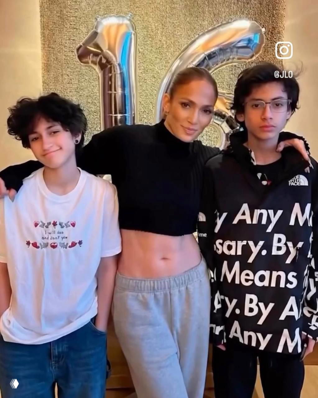 Женщина в спортивном топе позирует с двумя подростками на фоне праздничного декора и воздушных шаров; семейный снимок на вечеринке