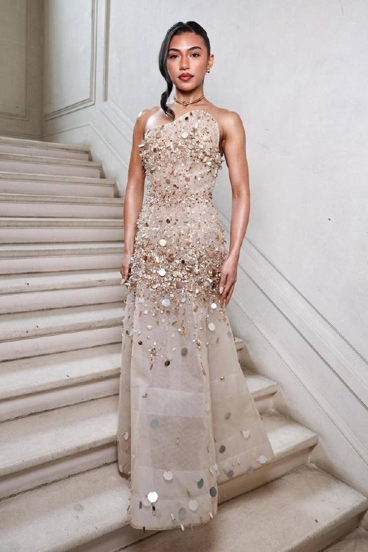 Модель в бежево-золотистом платье, украшенном пайетками и декором, образ с сиянием и фактурной отделкой на лестнице фотозоны.