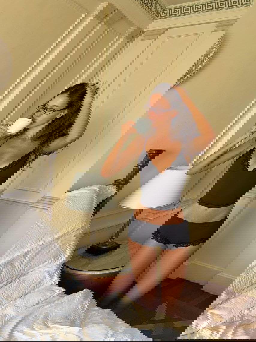 Девушка в чёрном белье в спальне с чашкой — естественный кадр, подчёркивающий комфорт, уверенность и результаты ухода за кожей тела.