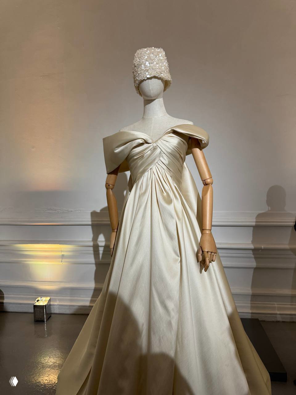 Кутюрное кремовое платье на манекене с пышной юбкой и детализированным верхом; экспозиция готового наряда в интерьере показа YUDASHKIN.