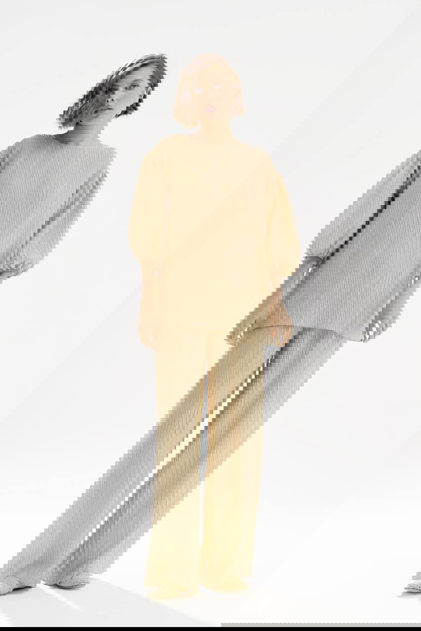 Фотография коллекции Nelva: модель в бежевом плиссированном костюме на светлом фоне, мягкий романтичный весенний образ и шёлковая фактура.