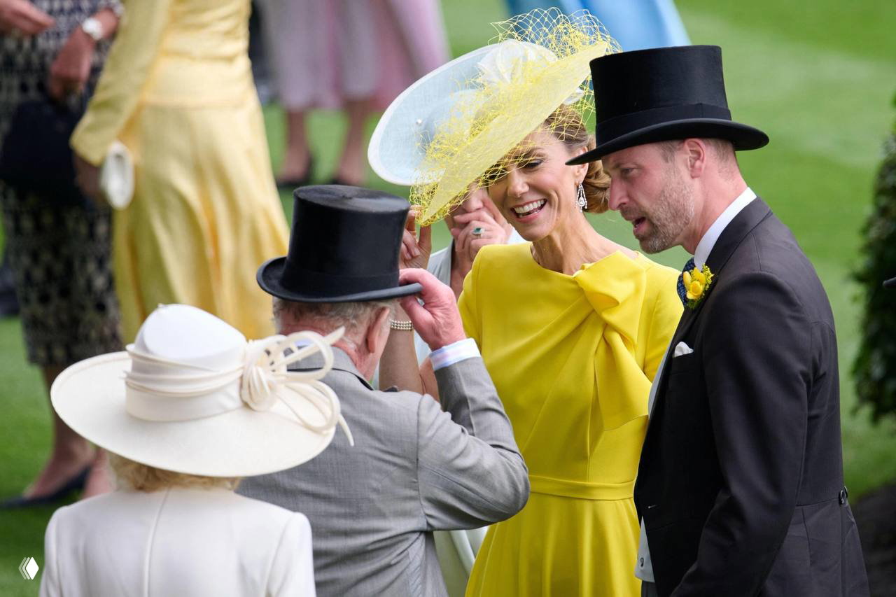 Женщина в жёлтой шляпе улыбается и общается с гостями на Royal Ascot; рядом мужчины в цилиндрах, зелёная трава и фотографы фиксируют момент