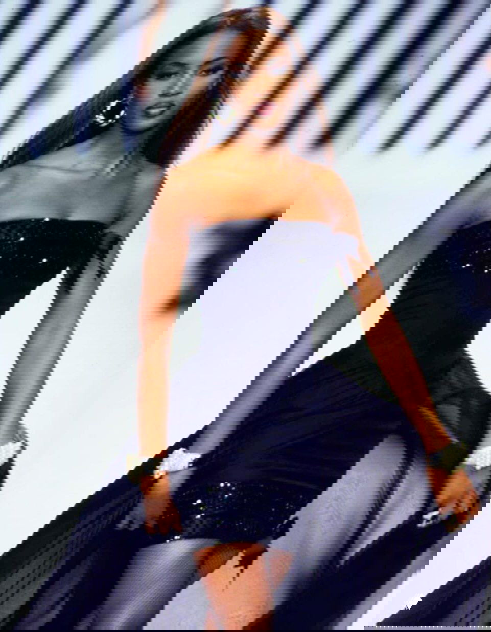 Модель в коротком чёрном корсетном платье дефилирует по подиуму, торжественный образ в классическом стиле показа.