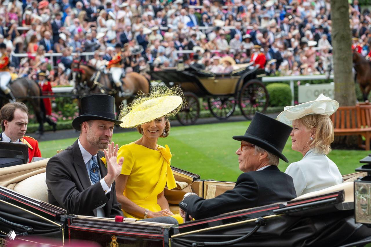 Женщина в жёлтом платье и мужчина в фраке машут публике из кареты на Royal Ascot; на заднем плане видна толпа, лошади и процессия