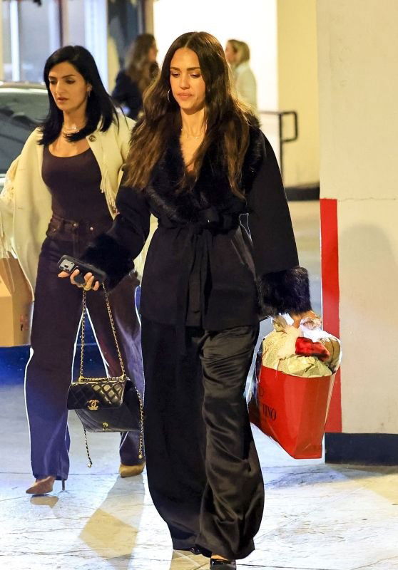 Две женщины в тёмных нарядах в торговом центре; одна держит пакет с покупками, интерьер и коридор торгового центра в кадре.