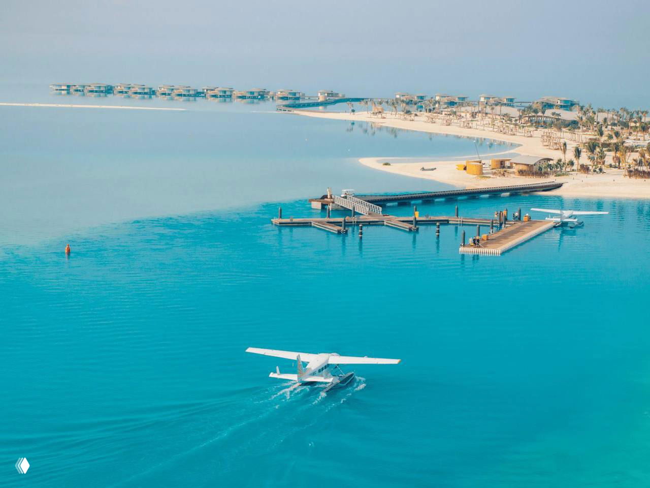 Гидроплан над бирюзовой водой курорта на Красном море, палубы, пляжи и надводные виллы на горизонте.