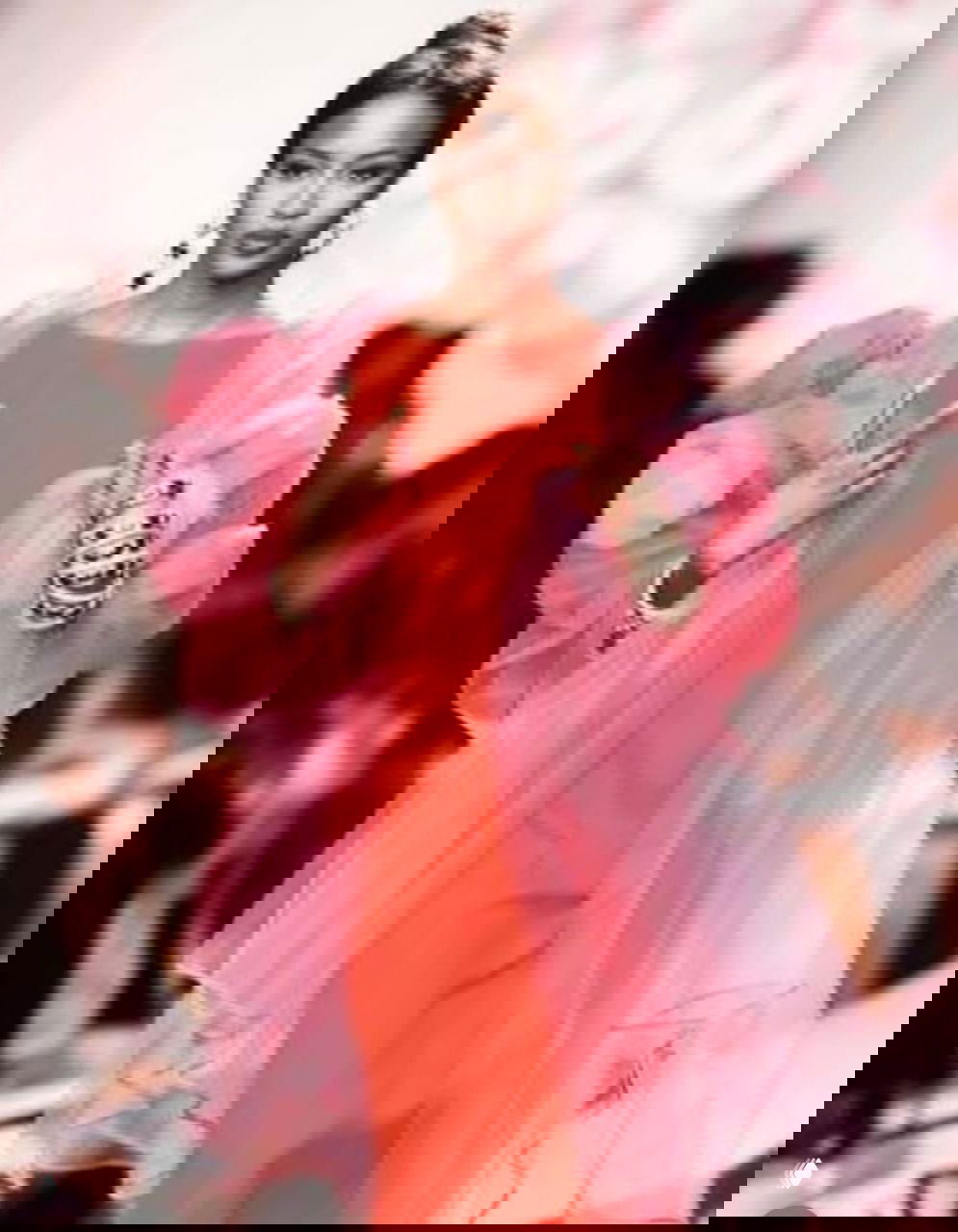 Модель в пышном розовом шарфе поверх красного платья шагает по подиуму; кадр передней линии коллекции, архивный снимок.