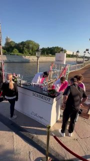 Выносной бар Schmidt на набережной Blogger Party: стойка у воды, гости подходят за коктейлями, видна река и зелёные берега в тёплый вечер.