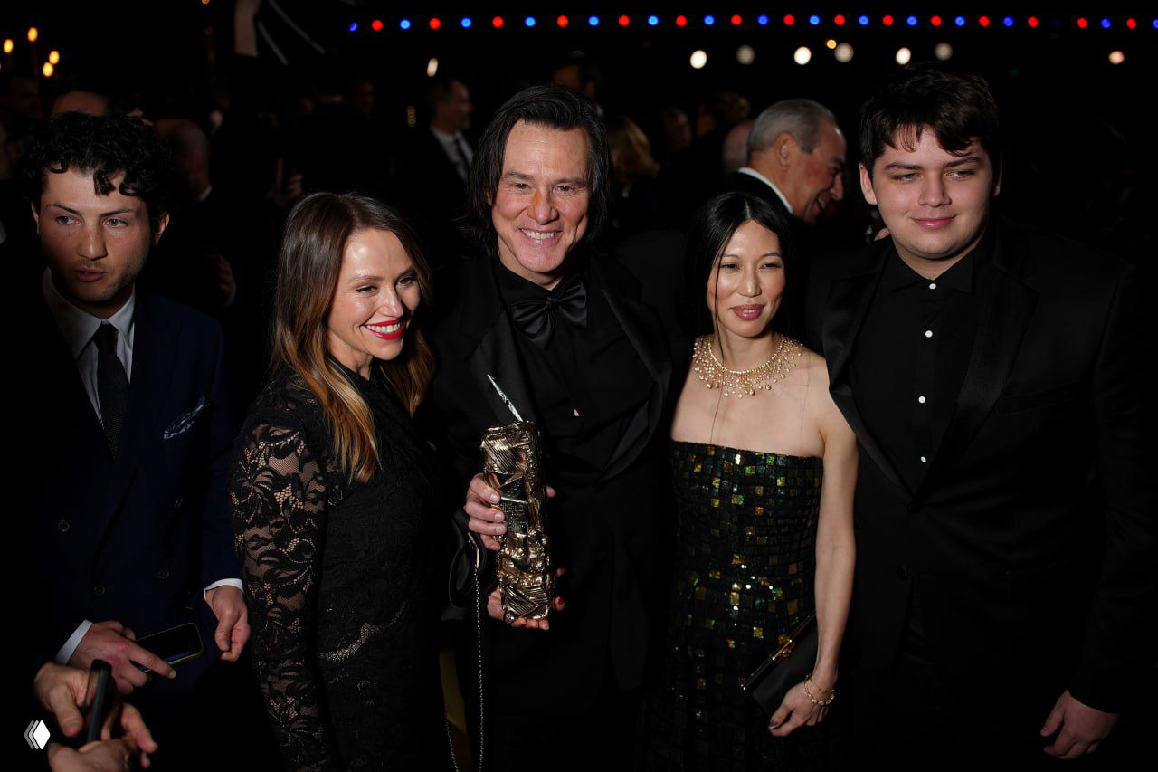 Джим Керри с наградой в окружении гостей на вечеринке после церемонии, рядом его спутница — художница Мина.