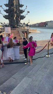 Гости на ступенях у набережной рядом с барной зоной Schmidt: люди в летней одежде, яркие ленточные украшения и общий вид площадки возле воды.
