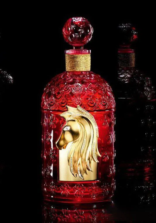 Фотография полного флакона Rouge Voluptueux: красное узорное стекло и золотая фигурка лошади от Truscelli, с кристаллами.