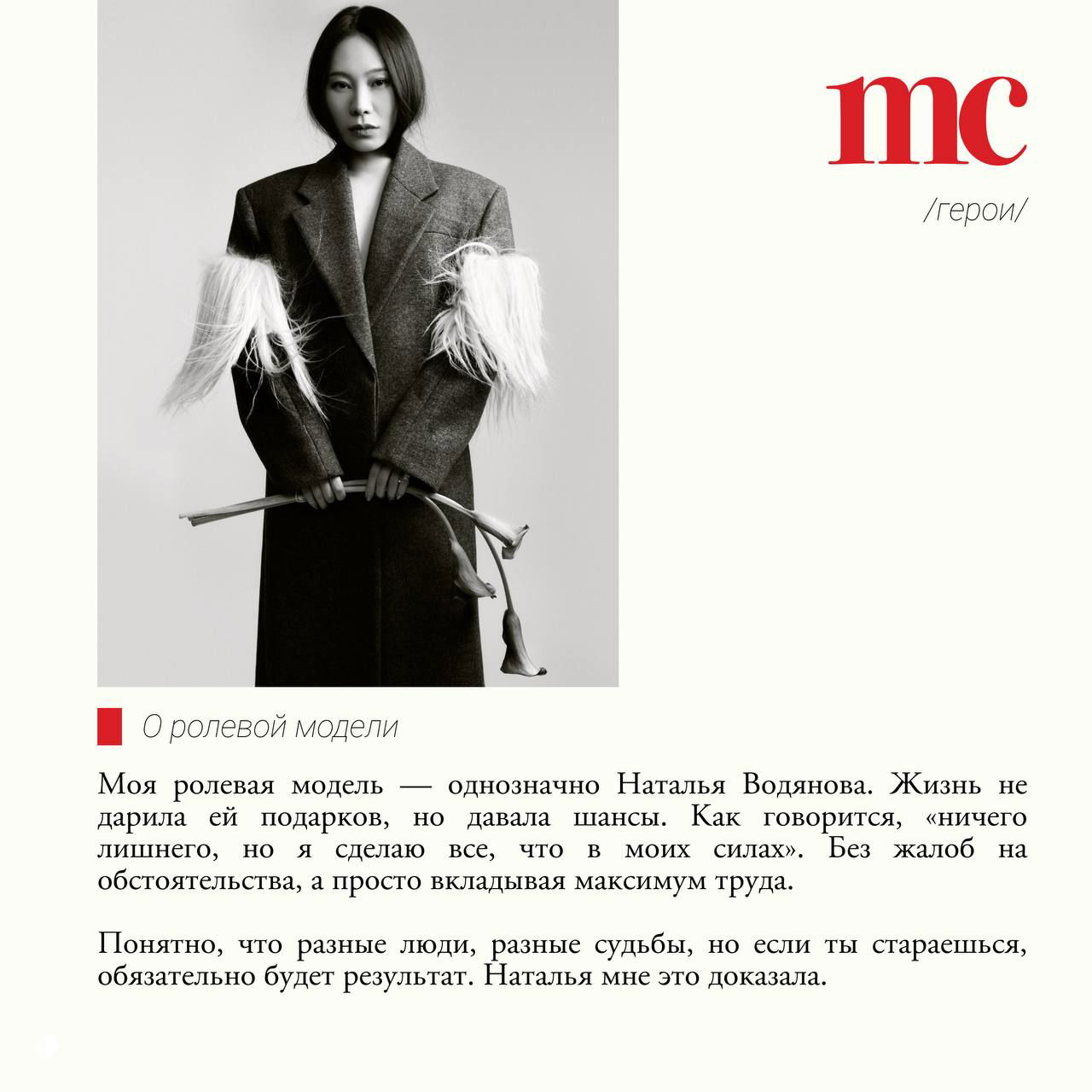 Полнотелая чёрно‑белая фотография женщины в длинном пальто, она держит декоративные цветы — стилизованная фэшн‑фотосессия.