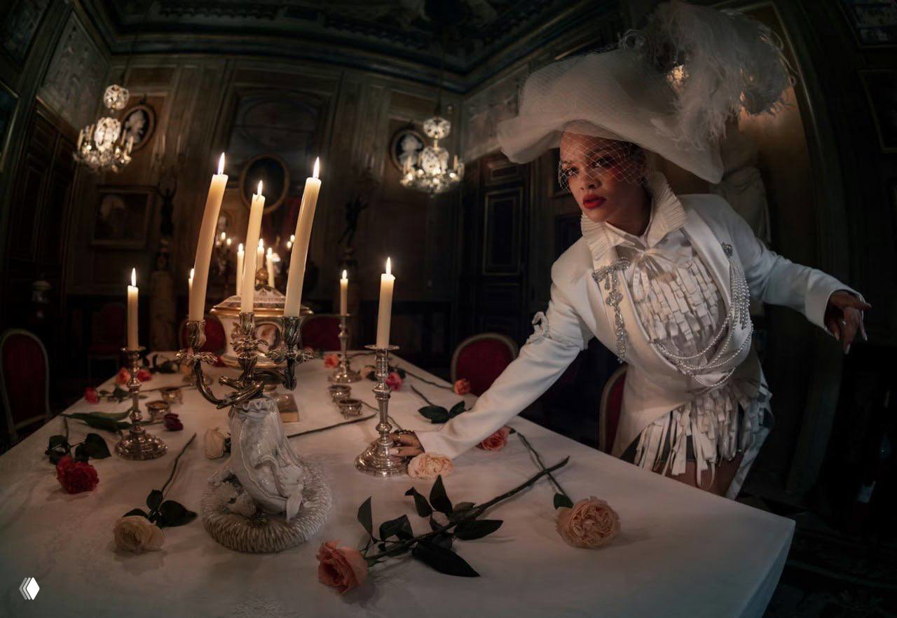 Рианна за столом с подсвечниками и розами, белый образ и шляпа — сценичное, театральное настроение съемки для W Magazine от Тима Уокера.