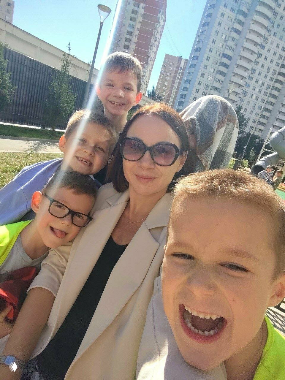 Воспитательница делает селфи с радостными детьми на площадке жилого комплекса — атмосфера прогулки и дружеских отношений в Клевер.
