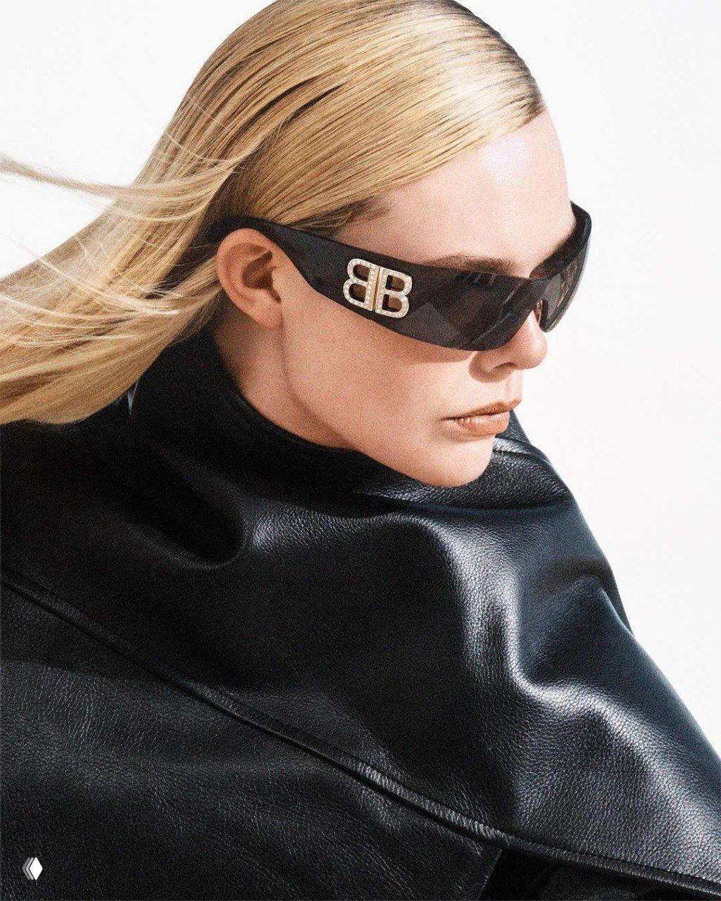 Портрет Эль Фаннинг в тёмных солнцезащитных очках с логотипом BB и кожаной накидкой: минималистичный образ и графичный профиль.