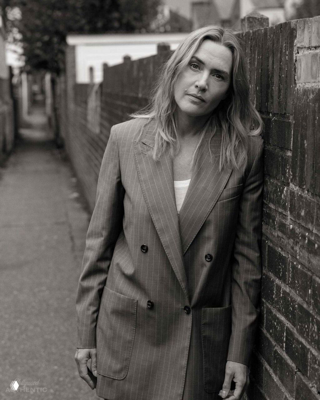 Крупный план женщины у кирпичного забора в узкой улице: портрет с мягким выражением и естественным образом съёмки.