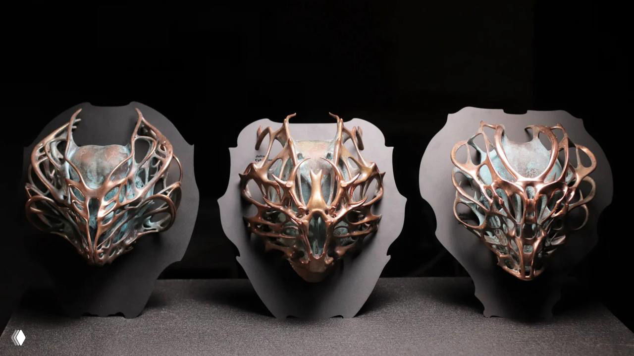 Фотография трёх декоративных бронзовых масок на тёмном фоне, видны орнаментальные рамы и скульптурная экспозиция галереи ASKERI.