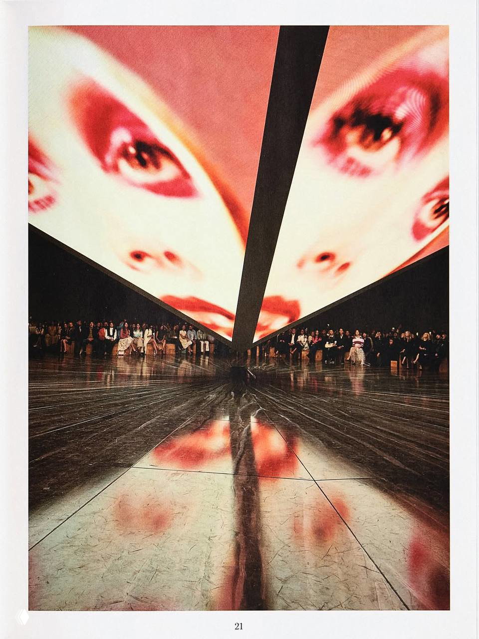 Кадр показа с огромным экраном, отражённым в полированном подиуме, и зрителями на трибунах — репортажная фотография с предпоказа весенней коллекции.