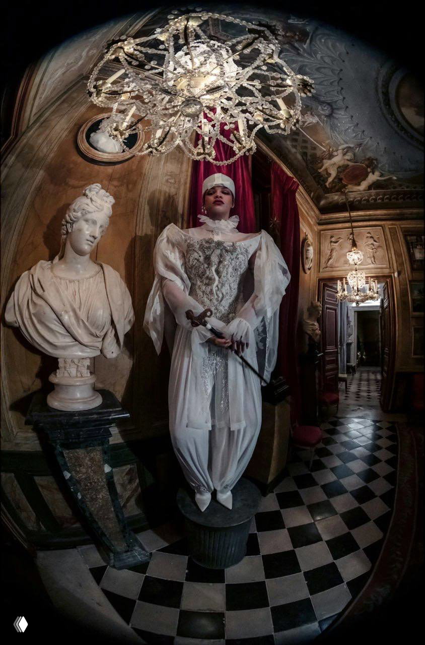 Рианна в длинном белом платье и аксессуарах, строгий реквизит и элегантность — кадр подчеркивает дизайнерские детали одежды и атмосферу съемки.