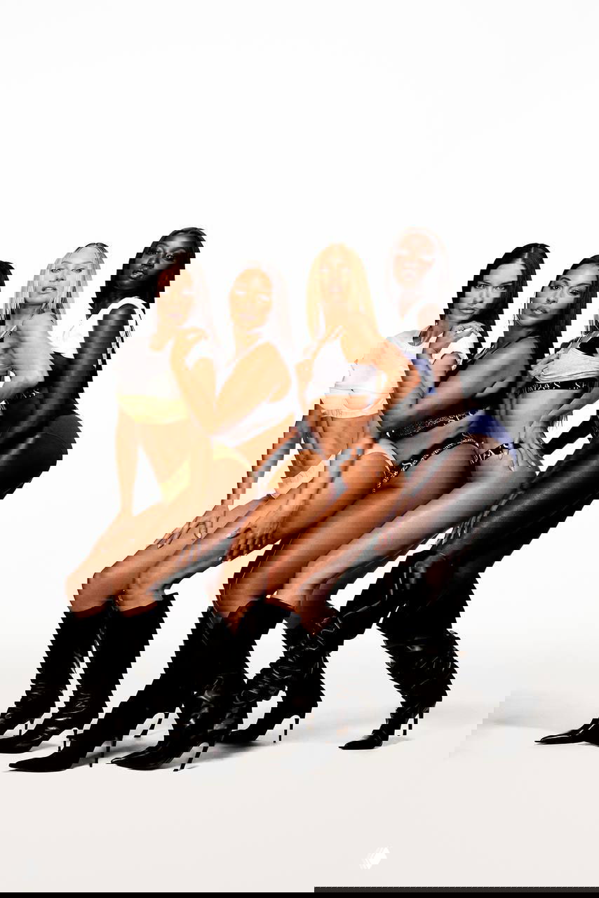 Групповая съёмка: четыре модели сближены в рекламной позе для новой коллекции Victoria’s Secret на нейтральном фоне.