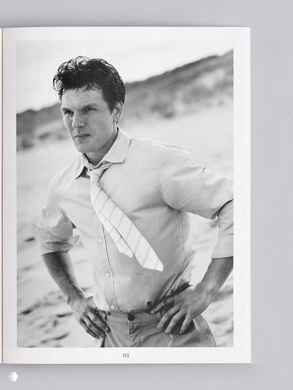 Чёрно‑белый портрет мужчины в рубашке и галстуке на фоне песчаного пейзажа — портретная фотография из разворота журнала, художественная съёмка.