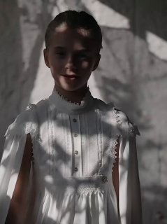 Девочка в белом кружевном платье Elie Saab в мягком боковом свете, акцент на текстуре и декоративных деталях коллекции.