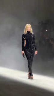 Кейт Мосс в чёрном платье закрывает показ Gucci: модель идёт по подиуму в дымовой атмосфере и приглушённом освещении.