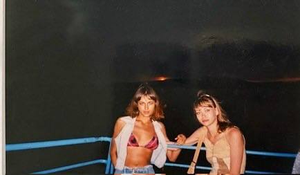 Ночной снимок: Ирина Шейк и подруга в купальниках и накидках находятся на открытой палубе или набережной — атмосфера вечера и отдыха.