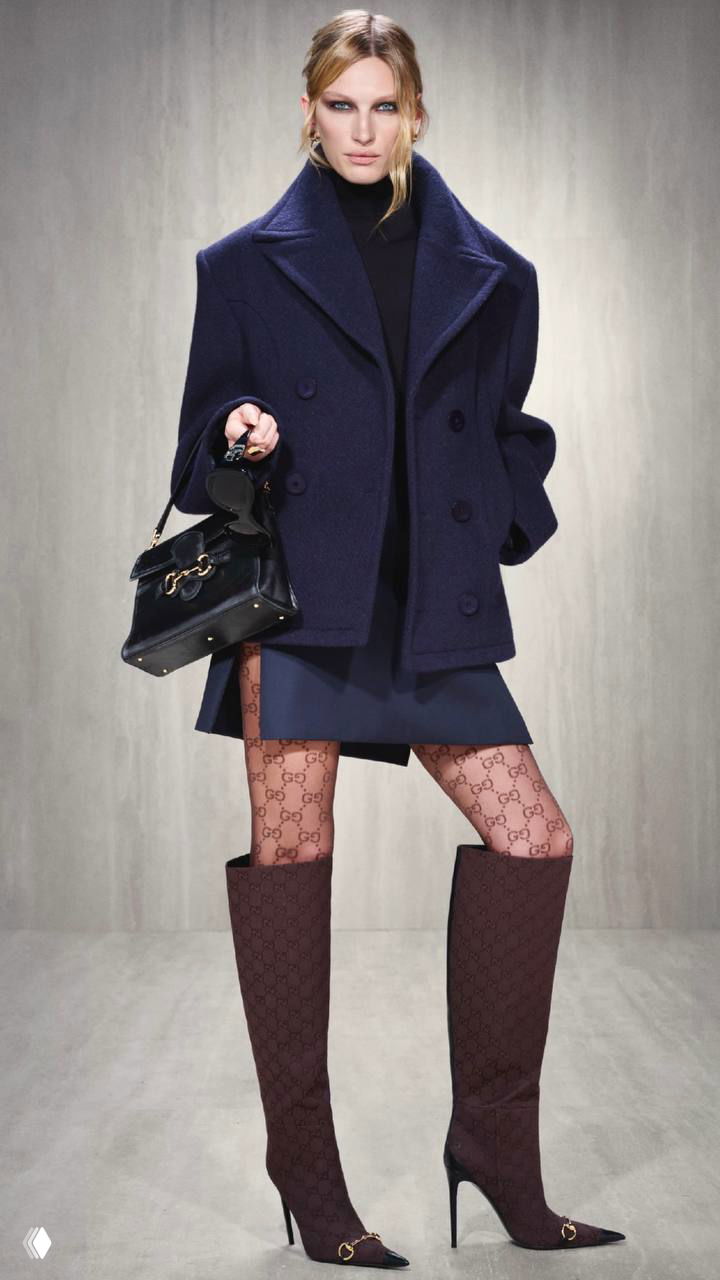 Жакет тёмно‑синего цвета с мини‑юбкой, чулки с логотипом и высокие сапоги — городской образ из коллекции Primavera.