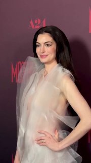 Энн Хэтэуэй на красной дорожке в светлом полупрозрачном платье на премьере «Мать Мария», виден фон с логотипом и фотографы