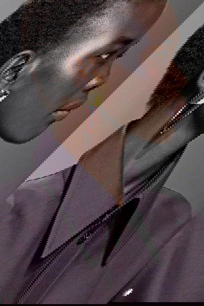 Профиль модели с серьгой-скульптурой: сочетание полированного металла и прозрачной вставки, эстетика крупной минималистичной формы.