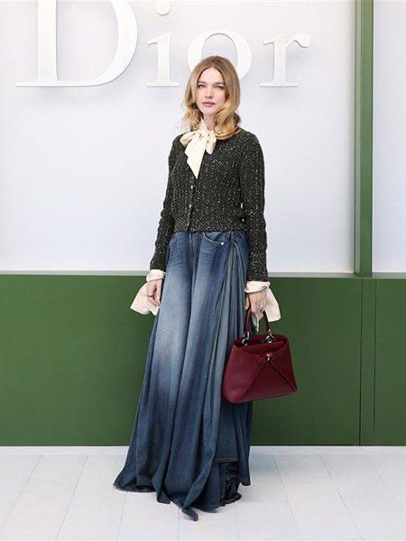 Рука держит черную сумку Dior Cigale крупным планом, видно тиснение 'Dior' и крупные металлические кольца на ручке, стильный аксессуар.