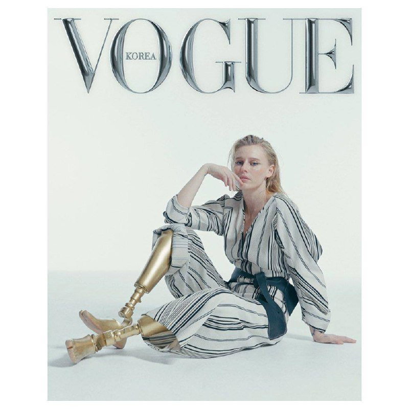 Минималистичная студийная съемка для Vogue Korea: Лорен сидит в светлом наряде, её золотые протезы лежат в кадре как важная часть композиции и имиджа.