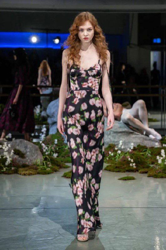 Модель в облегающем платье с цветочным рисунком шагает по подиуму, подчёркивая силуэт и авторскую обработку принта в показе Макдауэлла.