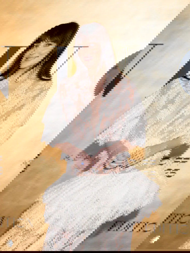 Крупный план Дакоты Джонсон в кружевном платье Chloé: V‑образный вырез, прозрачность ткани и нюдовый макияж на фоне золотой стены.