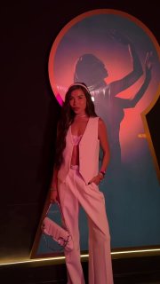 Модель в белом комплекте в бельевом стиле: жилет и открытый топ с сумкой в руке, образ подчёркивает бельевой тренд сезона