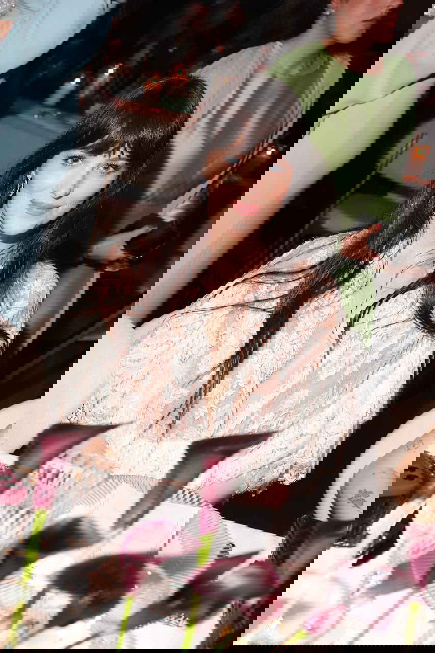 Дакота Джонсон за столом на гала-ужине «Женщины в кино»: кружевное платье Chloé, естественная улыбка и свечи на столе.