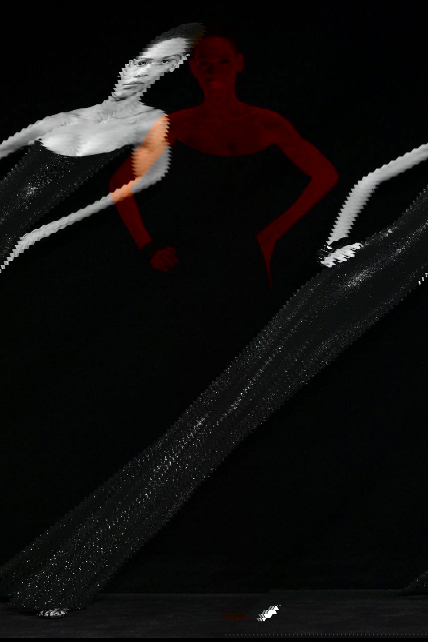 Модель в облегающем черном платье с корсетом Giorgio Armani на подиуме, лаконичный образ с акцентом на силуэт и блеск ткани при сценическом освещении.