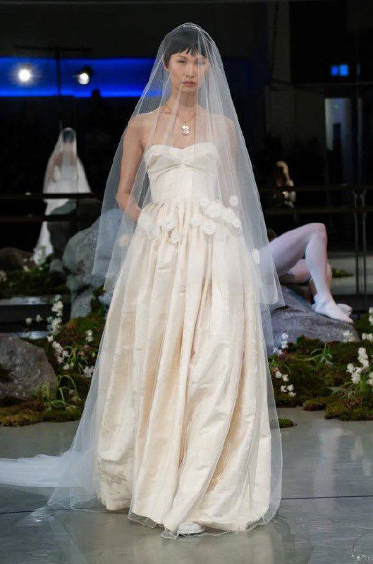 Модель в свадебном платье с фатой шагает по подиуму, показывая романтическую линию коллекции Патрика Макдауэлла на Лондонской Неделе моды.