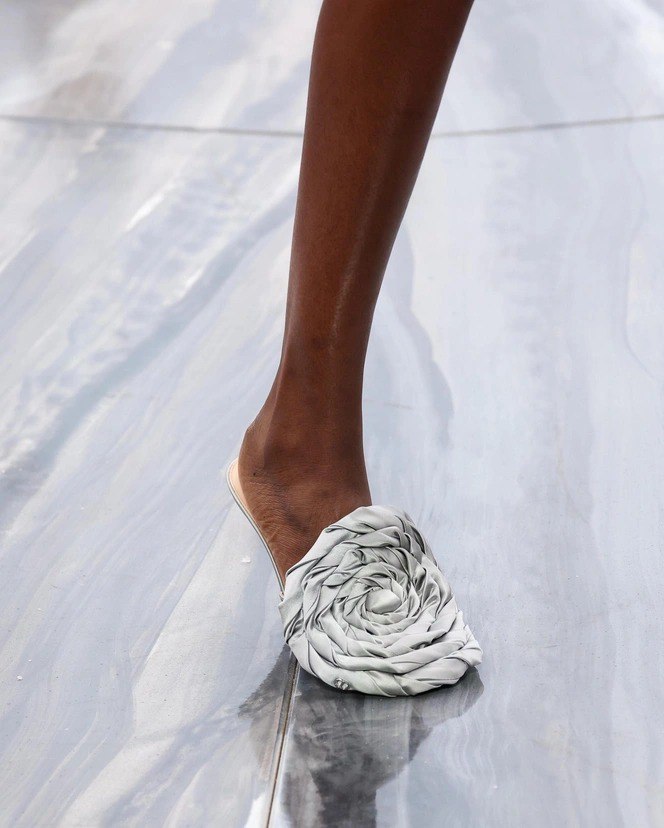 Крупный план босоножки: текстильная модель с закрученным декоративным элементом в виде бутона — пример тренда на «обувь‑героя» на подиуме.