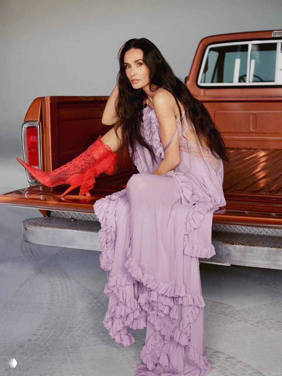 Нежный лиловый образ в длинном платье с рюшами на багажнике пикапа; контраст ярких красных сапог и пастельной ткани в кадре.