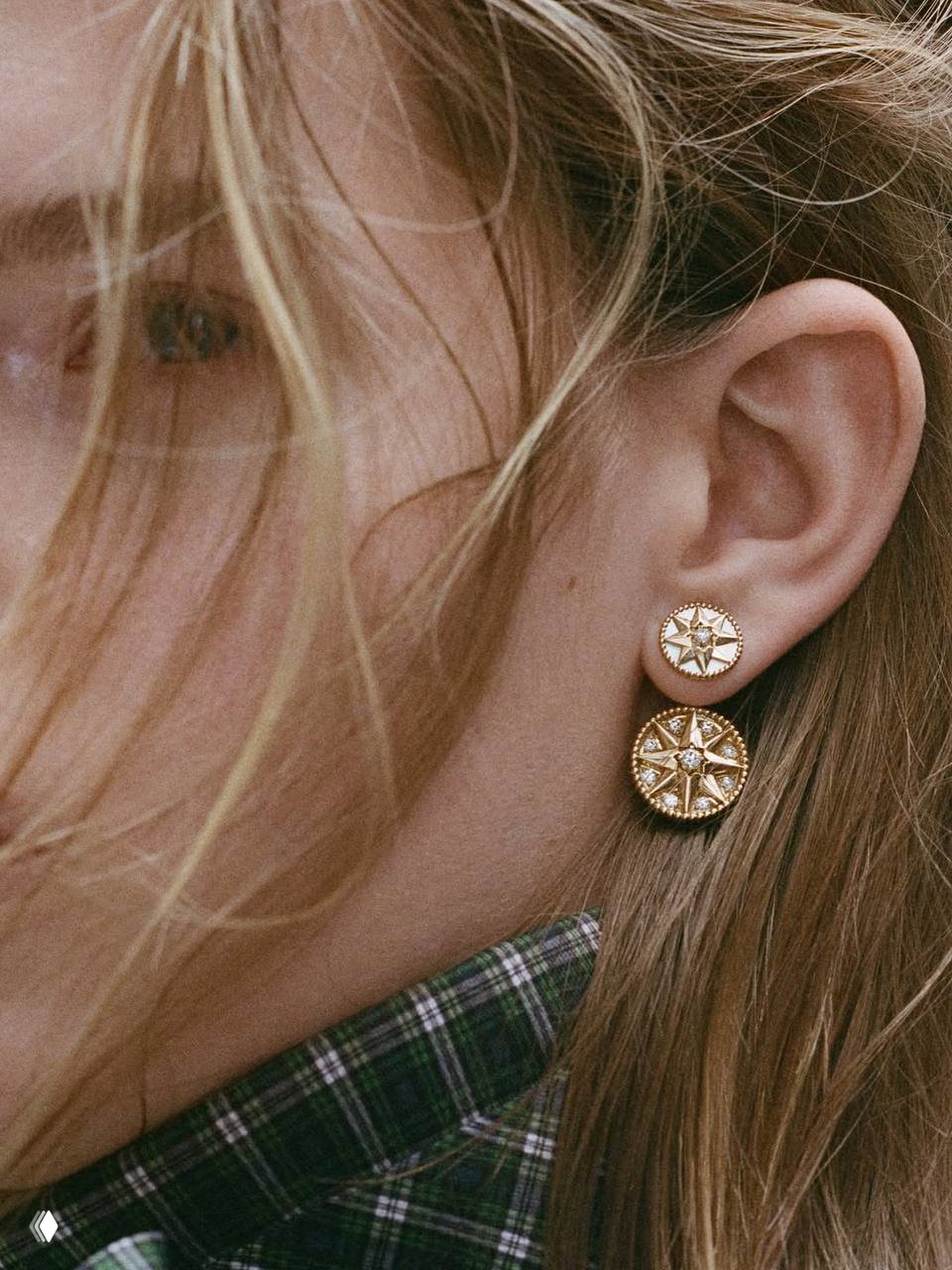 Крупный план серьги Dior с компасной розой, детальная окантовка и металлическая текстура на фоне кожи модели в лукбуке коллекции