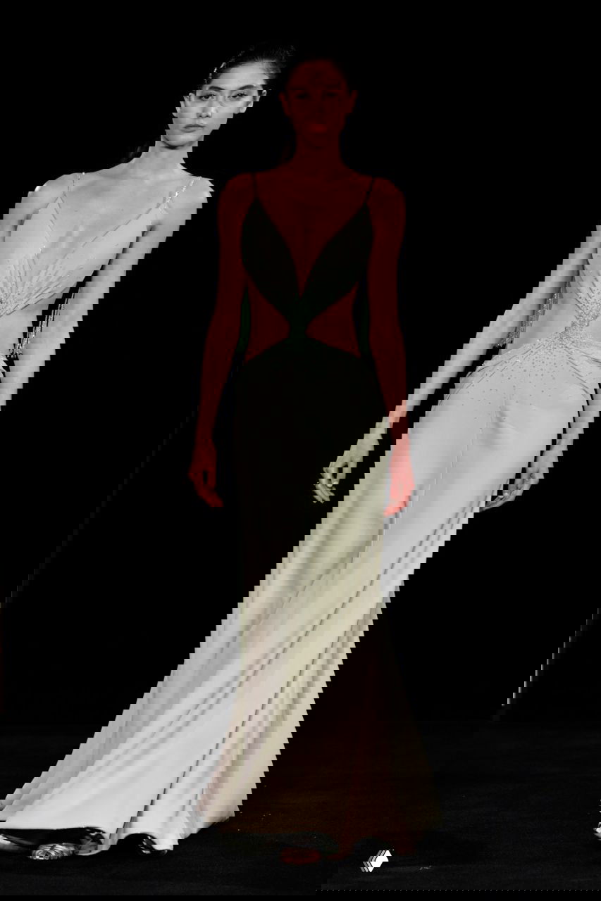 Длинный силуэт в мятно-пастельном платье со средним вырезом и скульптурными элементами по линии талии, образ из кутюрной коллекции Giorgio Armani на чёрном фоне подиума.