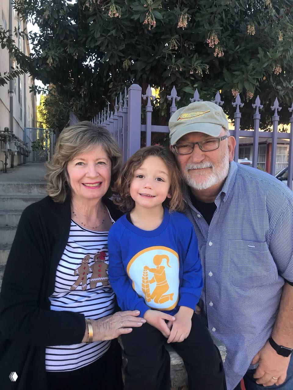 Семейный снимок: двое пожилых людей рядом с мальчиком, тёплый портрет трёх поколений на открытом воздухе в повседневной обстановке.