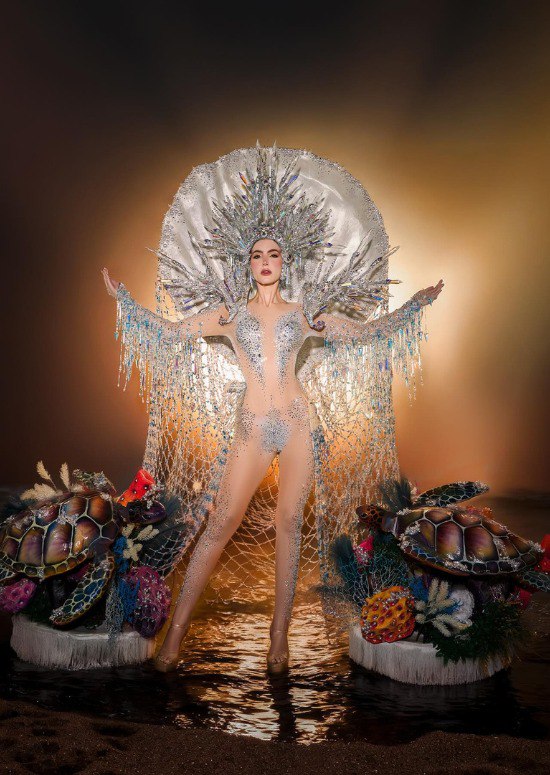 Серебристо‑белый наряд с кристаллами и декоративными элементами вокруг участницы, сцена украшена тематическими морскими пропсами и освещением.