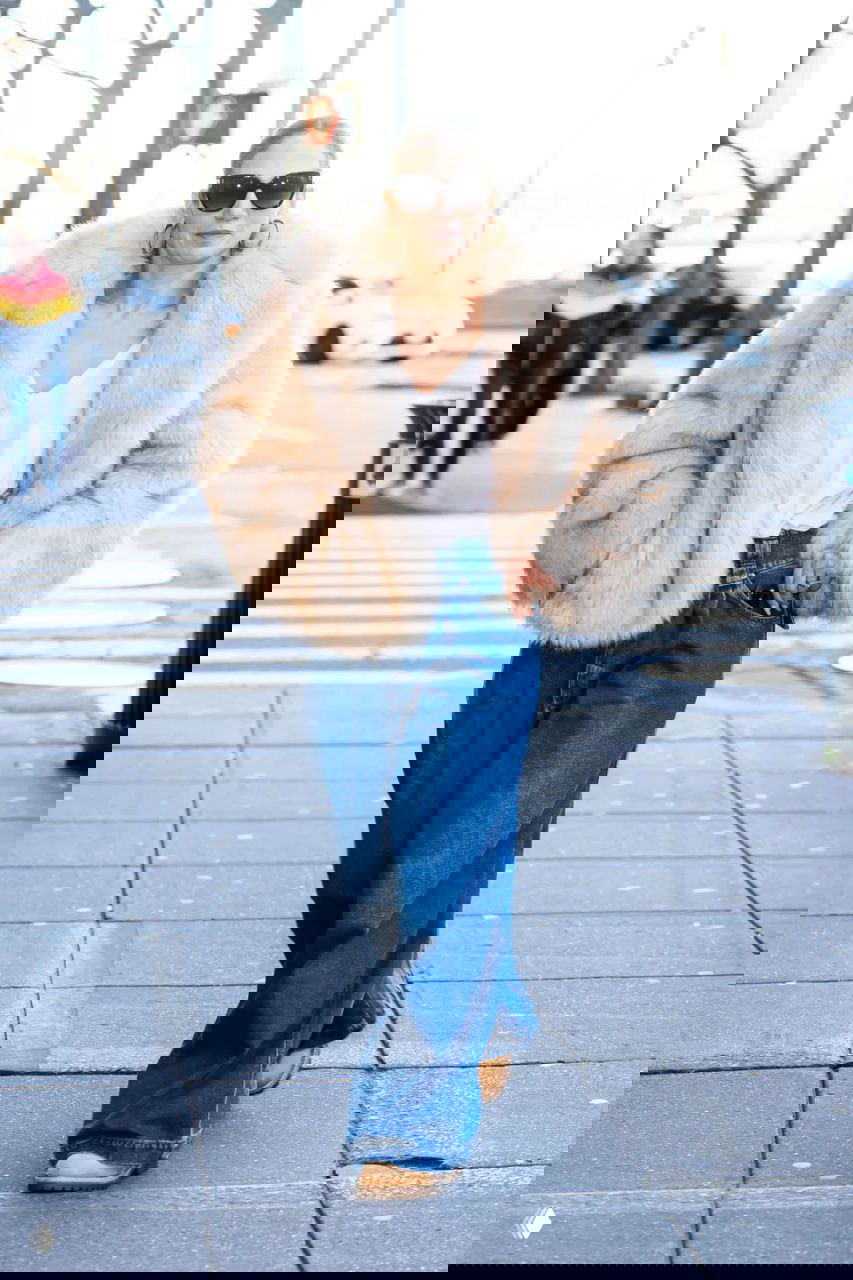 Короткая светлая меховая шуба в сочетании с широкими джинсами и обувью на низком ходу, уличная сцена в дневном свете.