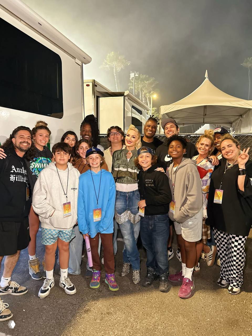 Групповое фото за кулисами с Гвен Стефани, детьми и командой артиста — дружеская сценическая атмосфера и командный снимок.