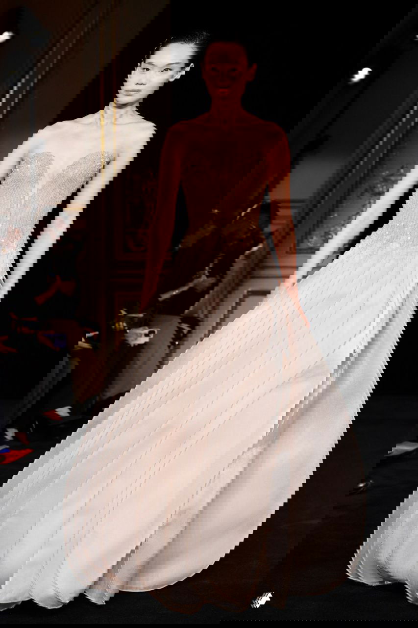 Модель в полупрозрачном платье с волнистыми декоративными элементами, плавный переход оттенков от нежно-розового к мятному на кутюрном показе Armani.